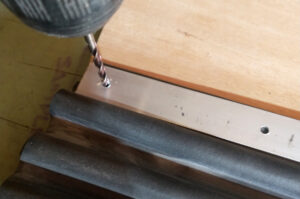 Placing the aluminum retailer over the robber boot and drilling pilot holes for to accommodate the screws or pop rivets